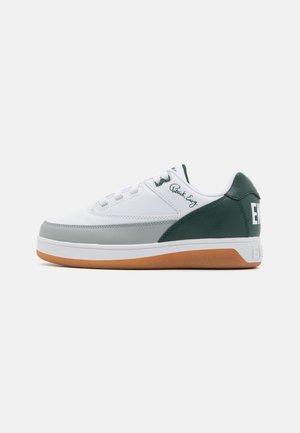 White athletic shoe with green accents and a gum rubber sole. Features smooth leather material and subtle pattern on the side.