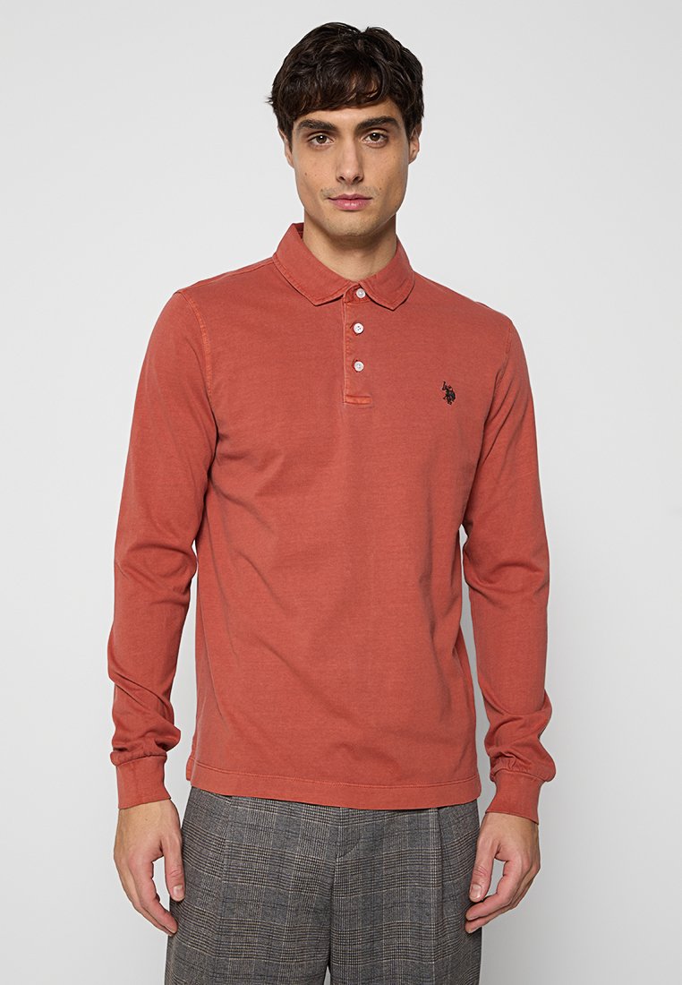Langärmliges Polo-Shirt aus gebranntem orangefarbenem Baumwollstoff mit einer Knopfleiste mit drei Knöpfen und schwarzem Logodesign auf der Brust. Klassisches Kragen-Design.