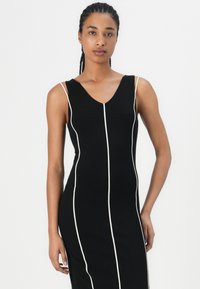 Black sleeveless dress featuring a V-neck, white vertical stripes, fitted design, and smooth fabric texture.