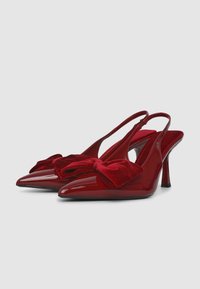 Rote Lackleder-Slingback-Absätze mit spitzem Zehenbereich, samtigem Schleifchen vorne und einem 10 cm hohen Stiletto-Absatz. Strukturierte Innenauskleidung.