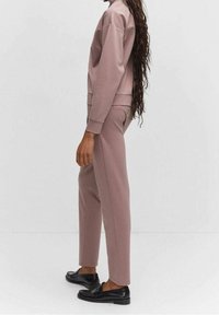 Sudadera rosa y pantalones ajustados a juego en una tela suave, con puños acanalados y un ajuste relajado. Mocasines negros completan el atuendo.