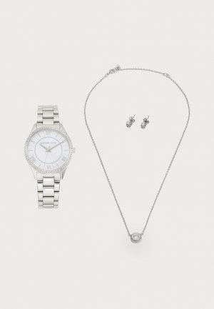 Orologio argento con quadrante bianco e numeri romani, circondato da cristalli; collana argento con un pendente centrale; orecchini a vite coordinati.