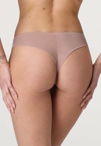 Perizoma color nudo realizzato in tessuto liscio; presenta un taglio a vita bassa e una copertura minima con bordi senza cuciture.