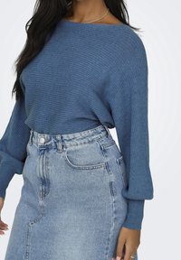 Blå ribbad tröja med bred båturringning, kombinerad med en högmidjad ljusblå denimkjol med slits fram och klassisk fickdesign.