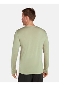 Langärmliges Shirt in Hellgrün, aus strukturiertem Stoff, mit rundem Halsausschnitt und lockerer Passform, sichtbaren Nähten und einem schlichten Rücken.