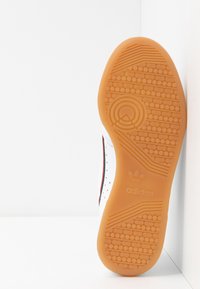 Vit sneaker sula med en orange gummibotten. Texturerad för grepp med cirkulära mönster. Har lila och röda detaljer längs sidan.