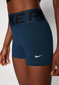 Shorts deportivos de Nike en azul marino con una cinturilla negra que presenta "NIKE PRO" y un logo blanco. Fabricados con un material elástico y costuras planas.