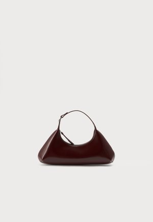 Borsa a mano triangolare in pelle marrone scuro con una singola tracolla corta e chiusura con zip su uno sfondo chiaro e uniforme.