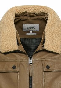 Tanfarbene Lederjacke mit einem flauschigen cremefarbenen Kragen, Front-Reißverschluss und schwarzen Akzenten. Enthält ein Etikett und ein strukturiertes Innenfutter.