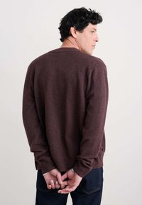 Bordo adīts džemperis ar apaļu kaklu, ar ribotām piedurknēm un apakšmalu. Aizmugurē ir vienkāršs, klasiskā dizaina izskats bez redzamām logo.