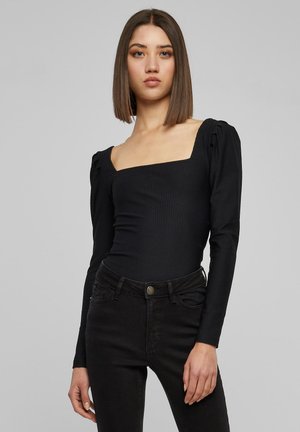 Zwart geribbeld lichaam met een vierkante halslijn en opstaande lange mouwen, gecombineerd met hoge taille zwarte jeans. Glad textuur, getailleerd ontwerp.