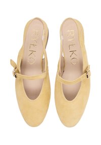 Sárga velúr pántos cipők bokapánttal és lekerekített orral. Puha tapintású, kivágásokkal díszítve, arany logóval a talpbetéten.