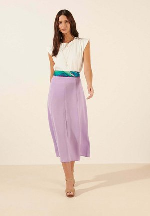 Haut blanc à manches courtes, jupe violette mi-longue et ceinture à motifs turquoise. Porté avec des sandales beiges à bride cheville. Texture lisse dans l'ensemble.