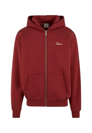 Burgundowa bluza z kapturem na zamek błyskawiczny, z kieszenią z przodu, ribbowanymi mankietami i dolnym brzegiem. Posiada jasnosrebrny logo na lewej piersi. Miękka textura materiału.