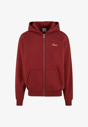 Burgundowa bluza z kapturem na zamek błyskawiczny, z kieszenią z przodu, ribbowanymi mankietami i dolnym brzegiem. Posiada jasnosrebrny logo na lewej piersi. Miękka textura materiału.