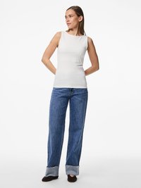 Vit ärmlös topp med hög halsringning, ihop med blå vida jeans med fransad nederkant och mörka skor. Enkelt och rent design.