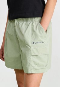 Pantalones cortos cargo de color verde claro con cintura elástica, bolsillos laterales y un logo de Columbia en la pierna. Fabricados con un material ligero y suave.