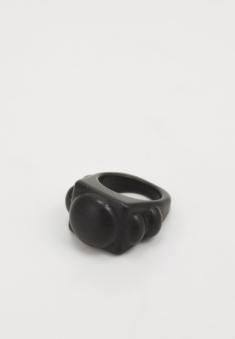 Black resin ring featuring a chunky design with rounded accents. The surface is smooth with a matte finish, emphasizing its bold shape.