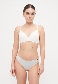 Witte beha met dunne bandjes en een diepe V-halsontwerp, gecombineerd met lichtgrijze naadloze bikini-slipjes met een klein logo.