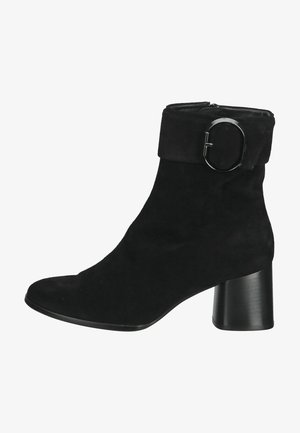 Black suede ankle boot with a chunky black heel, featuring a wide cuff and a round metallic buckle as a notable accent.