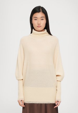 Cream-colored turtleneck sweater with a loose fit, ribbed cuffs, and a slightly fringed hem. Soft texture and gradual color gradient.