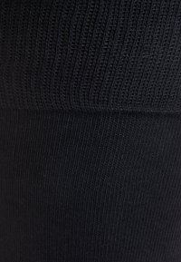Tessuto nero a costine con una superficie liscia, caratterizzato da una fascia orizzontale nella parte superiore e strisce verticali su tutto il tessuto.