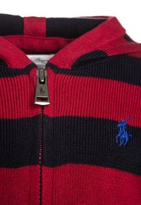 Maglione lavorato a maglia con zip, a righe rosse e blu navy, con texture a coste e zip in metallo, caratterizzato da un piccolo logo ricamato blu sul petto.