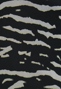 Μαύρο ύφασμα με υφή ζέμπρας που έχει έντονες, ανομοιόμορφες λευκές και κρεμ ρίγες. Ο σχεδιασμός δημιουργεί μια δυναμική, πολυεπίπεδη εμφάνιση.