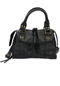 Sac à main en cuir noir au design structuré, doté d'une fermeture à glissière, de liens décoratifs, de quincaillerie en laiton et de poignées courtes.