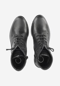 Bottines en cuir noir avec des bouts arrondis, des lacets et des zips sur le côté. Texture lisse, matériel minimal, lignes épurées et design simple.