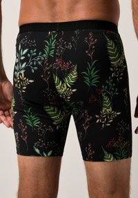 Černé boxerky s květinovým vzorem v zelené, červené a jemně přírodní barvě. Vyrobené z měkkého, elastického materiálu s pevným pasem.