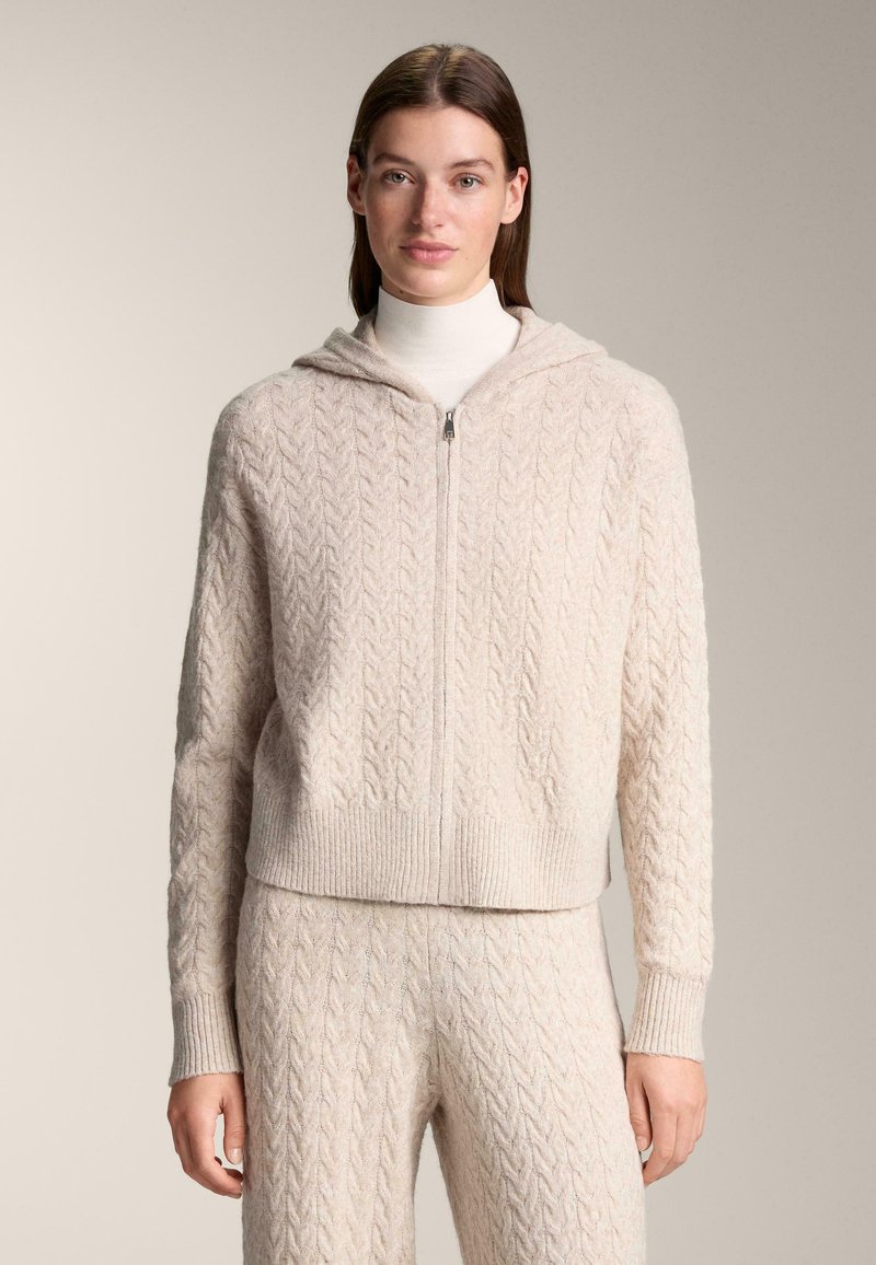 Krémově zbarvená mikina na zip s pleteným vzorem, žebrovanými manžetami a lemem, s kapucí a měkkou texturou, ve stejném designu doplněná kalhotami.