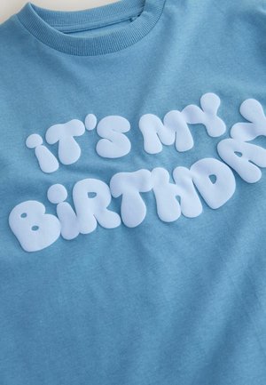 Hellblaues Baumwoll-T-Shirt mit weißem, abgerundetem, aufgeplustertem Schriftzug "it's my birthday." Rundhalsausschnitt, glatte Textur.