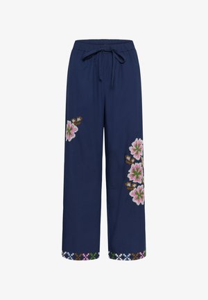 Sötétkék, bő szárú nadrág, rugalmas derékkal, rózsaszín, zöld és barna virágos hímzéssel a szárakon és az alján.