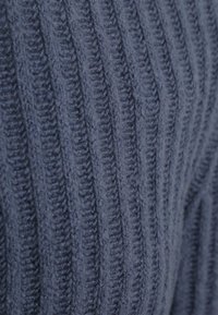 Marine rib gebreide stof met een zachte textuur, voorzien van verticale strepen en een chunky ontwerp dat diepte en dimensie benadrukt.