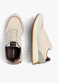 Zapatillas beige y gris claro con suelas de goma texturizadas, cordones y plantillas negras de marca con la etiqueta "Scalpers", mostradas desde vistas superior y lateral.