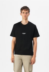 Sort bomulds t-shirt med rund hals og korte �ærmer, med "JJ Studios" logo i hvidt på venstre brystområde. Holdbart materiale.