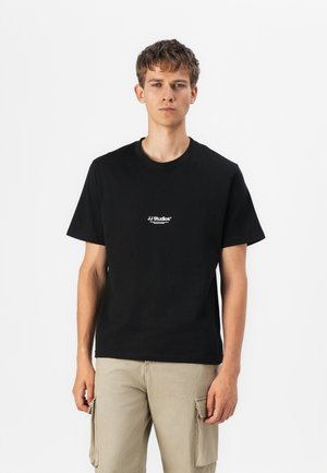Black cotton t-shirt with a round neck and short sleeves, featuring "JJ Studios" logo in white on the left chest area. Durable fabric.