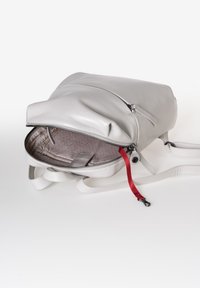 Zaino in pelle grigia con un vano principale con zip, nastro rosso decorativo e interno beige a fantasia. Presenta spallacci regolabili.