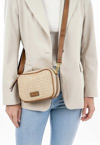Bolso bandolera tejido en beige con acentos de cuero marrón, forma rectangular, herrajes dorados y correa ajustable.
