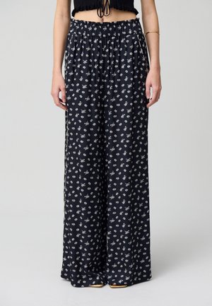 Pantaloni palazzo in un tessuto blu navy con una stampa floreale bianca. Vita elastica e vestibilità ampia, con copertura a lunghezza intera.