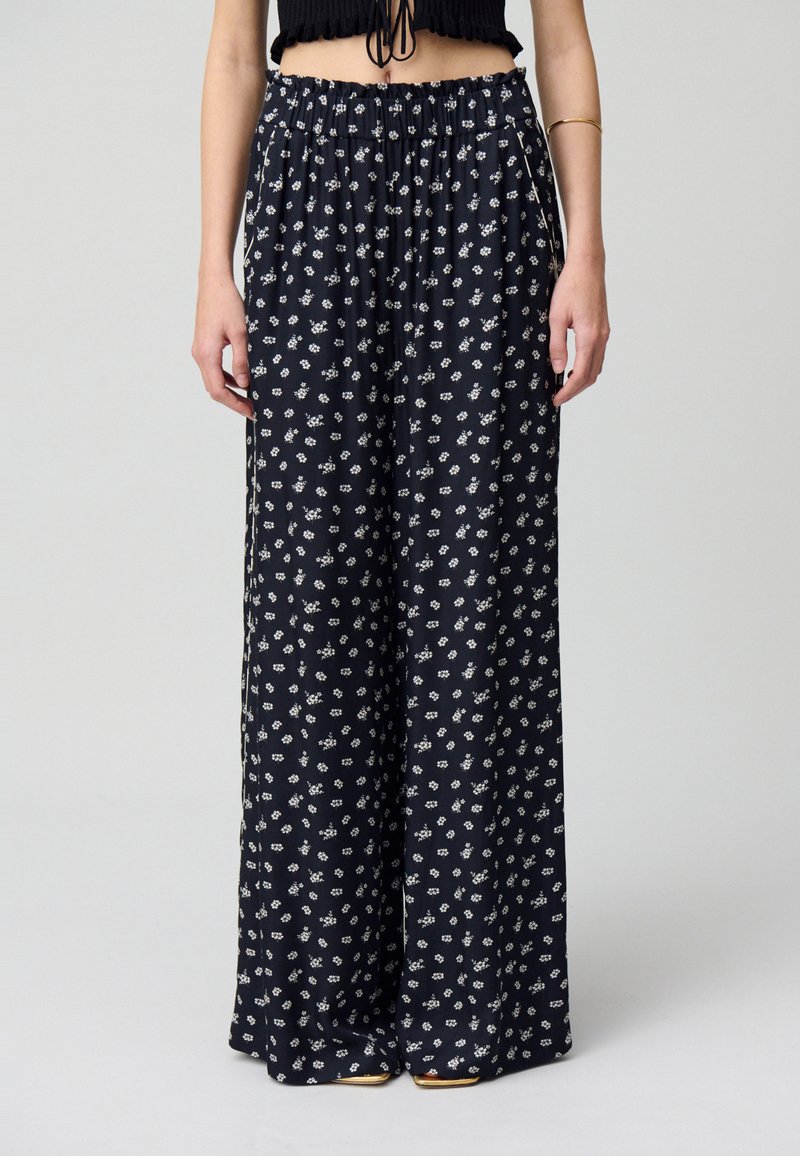 Pantalones Palazzo de tela azul marino con un estampado floral blanco. Cintura elástica y corte holgado, con cobertura completa en la longitud.
