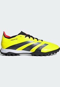 Chaussures de soccer jaunes et noires au design épuré, dotées de trois bandes noires, d'une surface texturée et d'une semelle blanche avec des crampons noirs.