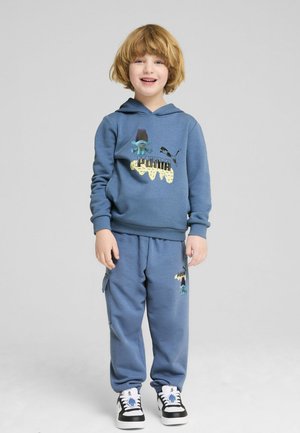 Blå huva och sweatpants-set med lekfulla grafiska tryck och en logotyp, tillverkat av mjukt tyg med ribbade ärmslut. Svartvita sneakers fulländar looken.