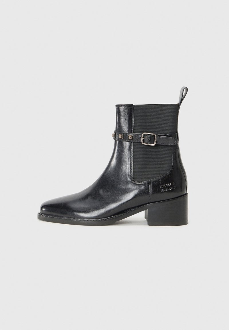 Bottine en cuir noir avec un bout pointu, des panneaux latéraux élastiques et une sangle décorative à boucle ornée de rivets. Design à talon carré.