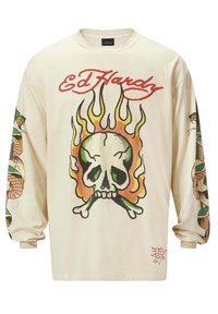 Langärmliges, cremefarbenes T-Shirt mit einem großen Totenkopf-Design, das von Flammen und Totenköpfen umgeben ist, verziert mit bunten Tätowierungen an den Ärmeln.