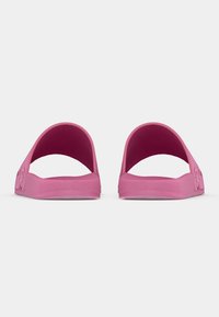 Pink slide sandals made of rubber with open-back design, featuring textured soles and subtle embossed detailing on the sides.