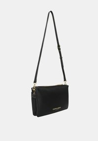 Borsa a tracolla in pelle nera con accessori dorati, chiusura con zip e tracolla regolabile. Presenta una superficie liscia e un logo impresso sul davanti.