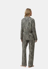 Schwarz-weiß gestreiftes Pyjama-Set mit langärmeligem Oberteil und passender Hose, aus einem weichen Material mit leichter Textur.