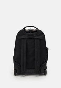 Schwarzer Rollenkoffer mit Stoffmaterial, verstellbaren Riemen und einem oberen Griff. Verfügt über eine strapazierfähige Basis und eine seitliche Netztasche.